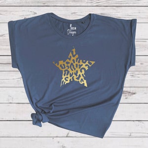 Pu&ograve; includere: Una maglietta blu navy con una stella dorata stampata sul davanti. La stella ha un design a stampa leopardata.