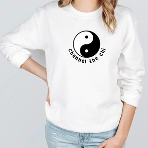 May include: White sweatshirt with a black yin yang symbol and the text "Channel the chi" printed on the front.