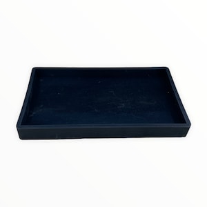 May include: A rectangular black tray with a slightly raised edge. The tray has a matte finish and appears to be made of a solid material. The interior of the tray is a dark, solid color.