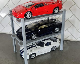 May include: A three-tiered metal shelf unit with three toy cars on it. The top car is red, the middle car is black, and the bottom car is white.