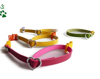 May include: Four colorful cat collars with silver heart charms. The collars are made of leather and have a buckle closure. The colors are pink, yellow, green, and purple.