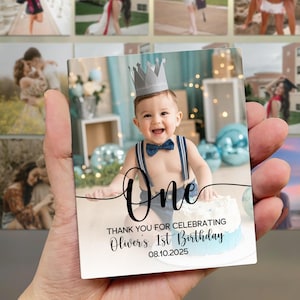 May include: A rectangular photo magnet featuring a smiling baby wearing a crown and bow tie, with the word "One" in script. The text "THANK YOU FOR CELEBRATING Oliver's 1st Birthday 08.10.2025" is also visible.