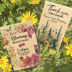 Puede incluir: Dos sobres de semillas con dise&ntilde;os florales y texto. Uno dice "Blooming Birthday Wishes, Evelyn's 30th Birthday 11.08.2025." El otro dice "Thank you for coming, Emma's 50th Birthday 11.8.2025." Los paquetes est&aacute;n rodeados de follaje verde y flores amarillas.