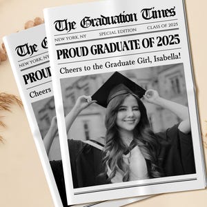 May include: Two newspapers titled "The Graduation Times" with the headline "Proud Graduate of 2025." The newspapers feature a black and white photo of a smiling graduate wearing a cap and gown. The text reads "Cheers to the Graduate Girl, Isabella!"