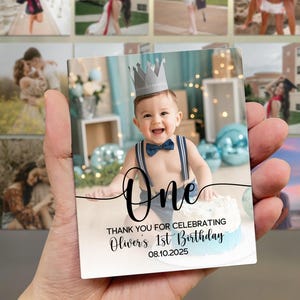 May include: A rectangular photo magnet featuring a smiling baby wearing a crown and bow tie, with the word "One" in script. The text "THANK YOU FOR CELEBRATING Oliver's 1st Birthday 08.10.2025" is also visible.