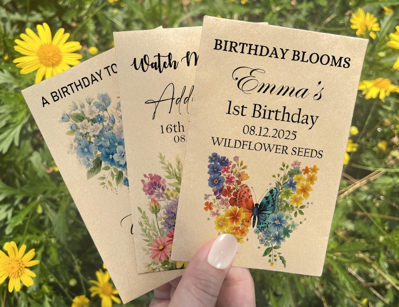 Puede incluir: Tres sobres de semillas con dise&ntilde;os florales y texto. Uno dice "A Birthday To", otro "Watch Me Add" y el tercero "Birthday Blooms Emma's 1st Birthday 08.12.2025 Wildflower Seeds". Los sobres presentan ilustraciones de mariposas azules, rosas y coloridas.