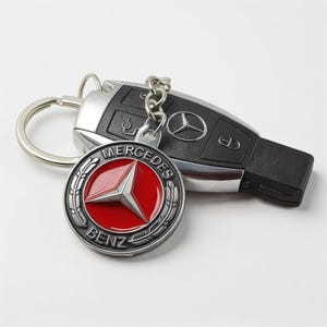May include: A black Mercedes-Benz car key and a matching keychain. The keychain features a red and silver emblem with the Mercedes-Benz logo and the word "BENZ". The key is black and silver.