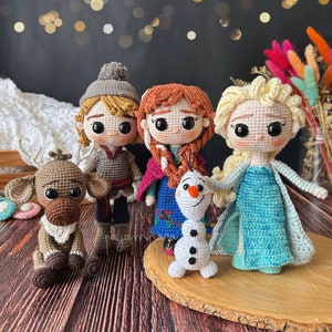 Könnte beinhalten: Ein Set aus fünf gehäkelten Figuren aus dem Film Frozen. Die Figuren sind Elsa, Anna, Kristoff, Olaf und Sven der Rentier. Die Figuren stehen alle auf einer Holzoberfläche.