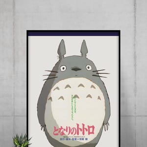Pode incluir: P&ocirc;ster emoldurado com o personagem Totoro do filme de anima&ccedil;&atilde;o "Meu Vizinho Totoro". A obra de arte retrata uma criatura grande, cinza e peluda com uma barriga branca e texto em japon&ecirc;s. O p&ocirc;ster &eacute; exibido em uma parede.