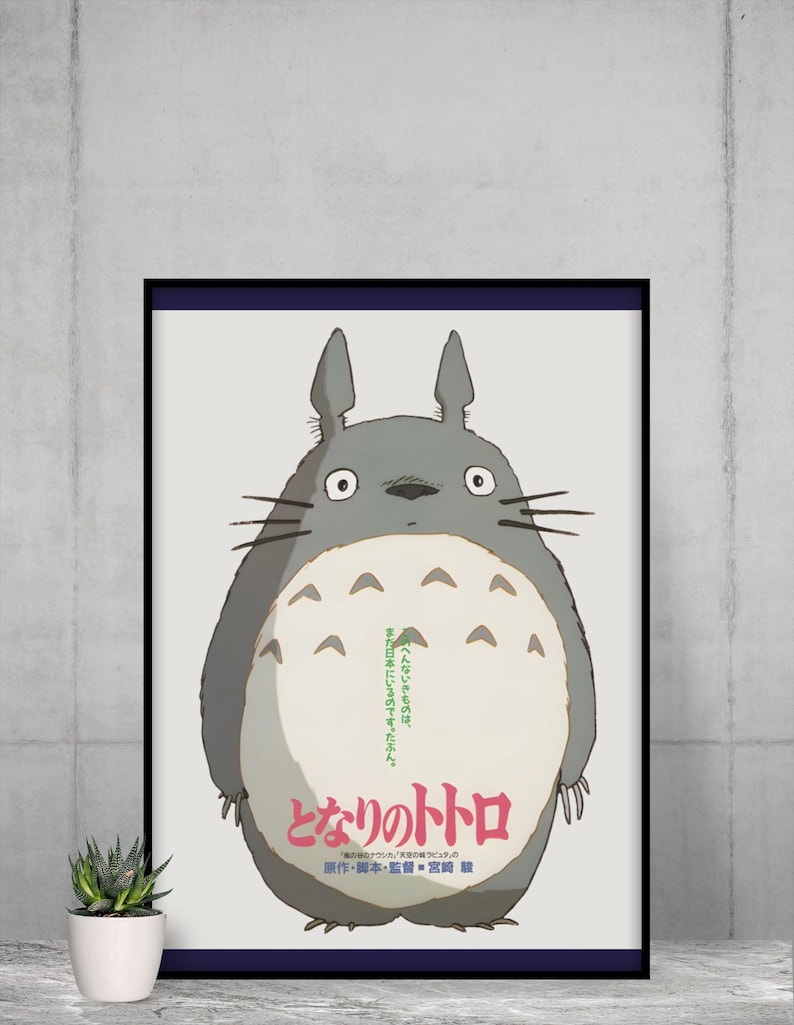Pode incluir: P&ocirc;ster emoldurado com o personagem Totoro do filme de anima&ccedil;&atilde;o "Meu Vizinho Totoro". A obra de arte retrata uma criatura grande, cinza e peluda com uma barriga branca e texto em japon&ecirc;s. O p&ocirc;ster &eacute; exibido em uma parede.