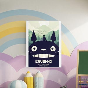 K&ouml;nnte beinhalten: Ein gerahmtes Poster mit einem dunkelblauen Totoro-Charakter mit einem breiten Grinsen und wei&szlig;en Augen. Der Hintergrund zeigt eine gr&uuml;ne Landschaft mit Bergen, B&auml;umen und V&ouml;geln. Japanischer Text ist sichtbar.