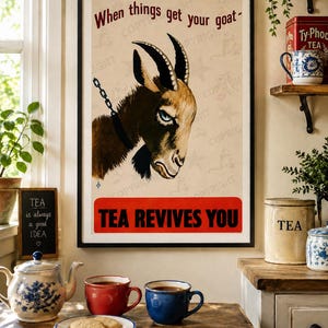 Könnte beinhalten: Ein gerahmtes vertikales Poster mit einer braunen Ziege mit Kettenhalsband und dem Text When things get your goat sowie TEA REVIVES YOU in fetter roter und schwarzer Schrift auf beigem Hintergrund mit blassem Sternenmuster.