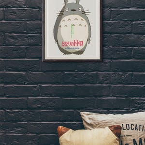 Pode incluir: P&ocirc;ster emoldurado com o personagem Totoro do filme de anima&ccedil;&atilde;o "Meu Vizinho Totoro". A obra de arte retrata o corpo cinza e redondo de Totoro com uma barriga branca, olhos grandes e bigodes. Texto japon&ecirc;s vis&iacute;vel na parte inferior.