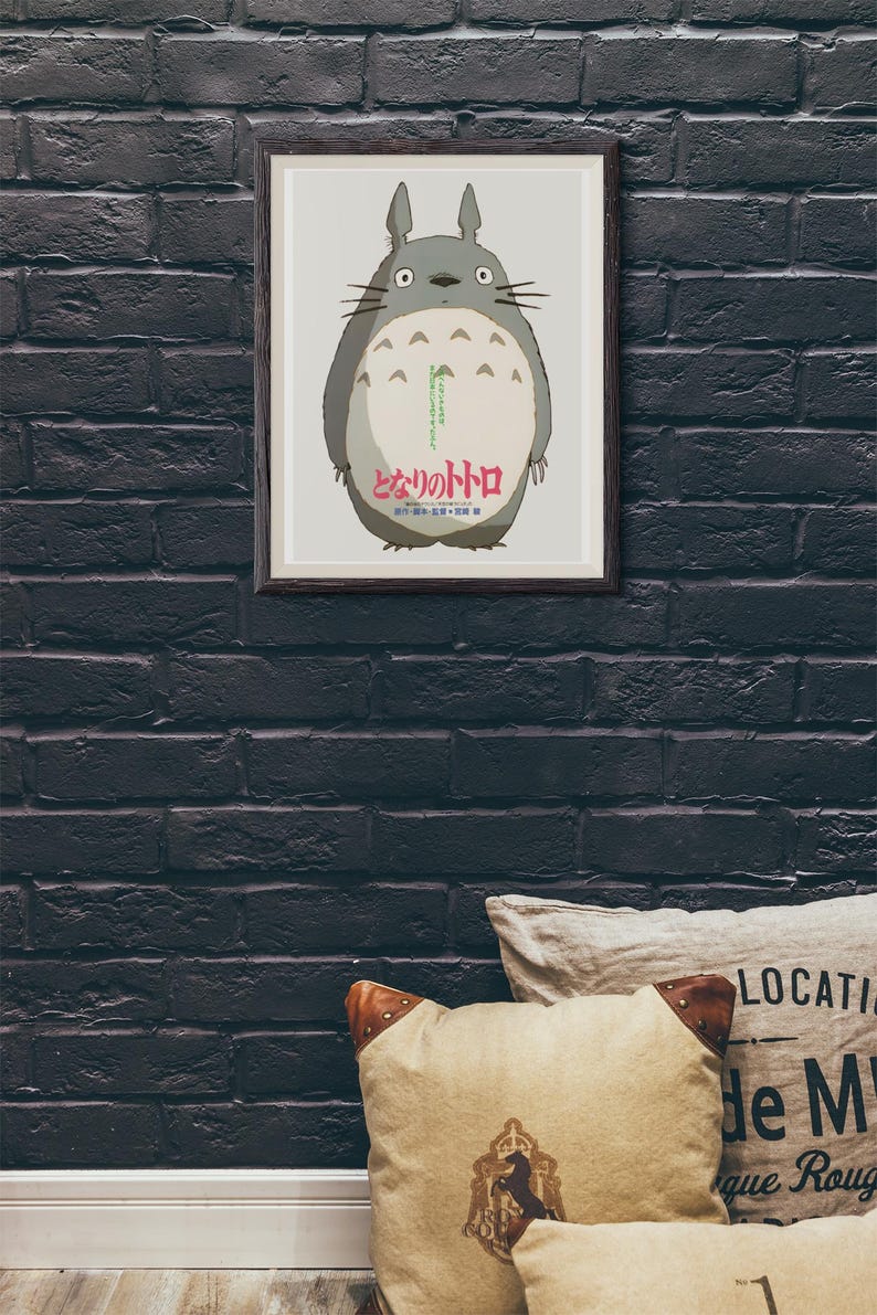Pode incluir: P&ocirc;ster emoldurado com o personagem Totoro do filme de anima&ccedil;&atilde;o "Meu Vizinho Totoro". A obra de arte retrata o corpo cinza e redondo de Totoro com uma barriga branca, olhos grandes e bigodes. Texto japon&ecirc;s vis&iacute;vel na parte inferior.