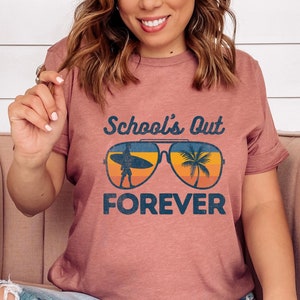 May include: A maroon t-shirt with the text "School's Out Forever" and a retro-style illustration of sunglasses with a palm tree and a surfer.