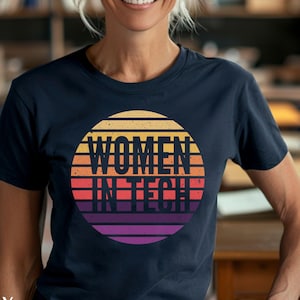 Puede incluir: Una camiseta azul marino con un gráfico de puesta de sol retro que dice "Women in Tech".