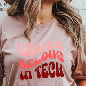 Könnte beinhalten: Ein T-Shirt in Heide-Mauve mit dem Text "Women Belong in Tech" in einer Retro-Schriftart.