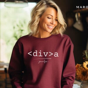 Puede incluir: Una sudadera color granate con el texto "<div>a Jennifer" impreso en blanco en la parte delantera.