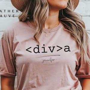 Puede incluir: Una camiseta de color malva jaspeado con el texto "<div>a" y el nombre "Jennifer" escrito debajo.