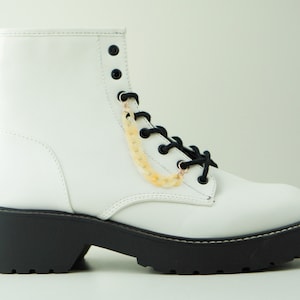 May include: White leather ankle boots with black laces and a chunky black platform sole.