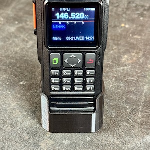 May include: A black handheld radio with a digital display showing the frequency 146.52000 and the call sign N3HAK. The radio has a keypad with numbers and letters, and a menu button.