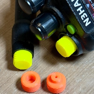 May include: A black handheld radio with the text "N3HAK" and black knobs. The radio has a yellow cap on the antenna and a yellow button. Two orange caps are also visible.