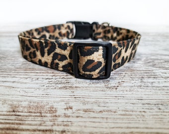 May include: A brown and black leopard print dog collar with a black plastic buckle.