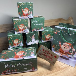 Puede incluir: Una colección de cajas de regalo y una bolsa de regalo con temática navideña. Las cajas y la bolsa son verdes con ilustraciones de Papá Noel, muñecos de nieve y árboles de Navidad. Las cajas tienen el texto "Merry Christmas".