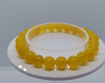May include: A yellow gemstone bracelet with round beads. The bracelet is on a white display stand.