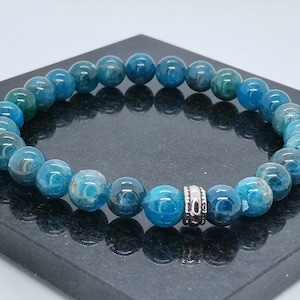 May include: A blue gemstone bracelet with silver accents. The bracelet is made of round beads and has a silver spacer bead.