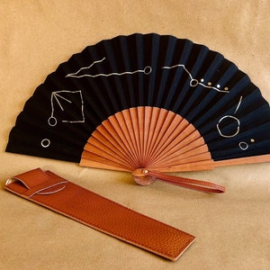 Black and gold hand fan made of wood & fabric with a geometric design from Berlin, matching vegan handmade cover and loop