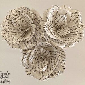 Puede incluir: Tres rosas de papel hechas con las p&aacute;ginas de libros antiguos. Las rosas est&aacute;n dispuestas en forma de coraz&oacute;n.