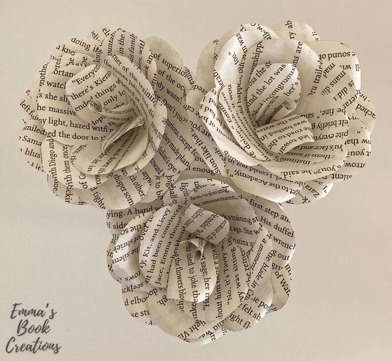 Puede incluir: Tres rosas de papel hechas con las p&aacute;ginas de libros antiguos. Las rosas est&aacute;n dispuestas en forma de coraz&oacute;n.