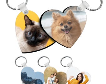 May include: Four heart-shaped keychains with different images. The top keychain features a cat and a dog. The bottom row features a mountain landscape, a family portrait, and a woman smiling.