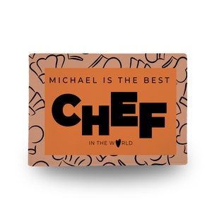Pu&ograve; includere: Carta arancione con un motivo di cappelli da chef bianco e nero. Il testo "MICHAEL IS THE BEST CHEF IN THE WORLD" &egrave; scritto in nero su sfondo arancione.
