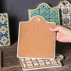 Puede incluir: Conjunto de cuatro salvamanteles de cer&aacute;mica con respaldo de corcho. Los salvamanteles presentan un patr&oacute;n geom&eacute;trico colorido inspirado en dise&ntilde;os tradicionales de azulejos.