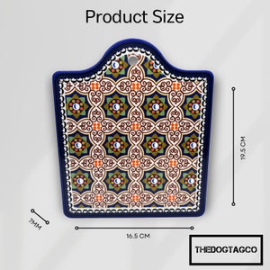 Puede incluir: Una tabla de cortar de cer&aacute;mica azul y blanca con un patr&oacute;n geom&eacute;trico. La tabla mide 16,5 cm por 19,5 cm.