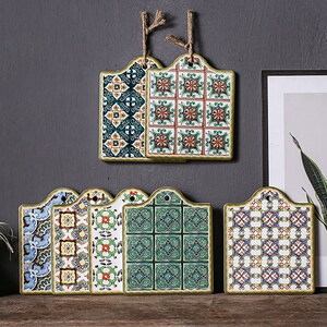 Puede incluir: Conjunto de seis salvamanteles de cer&aacute;mica con intrincados patrones geom&eacute;tricos en tonos de azul, verde, amarillo y rojo. Los salvamanteles tienen un borde festoneado y un agujero para colgar.