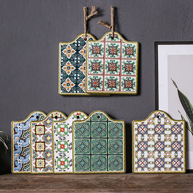 Puede incluir: Conjunto de seis salvamanteles de cer&aacute;mica con intrincados patrones geom&eacute;tricos en tonos de azul, verde, amarillo y rojo. Los salvamanteles tienen un borde festoneado y un agujero para colgar.