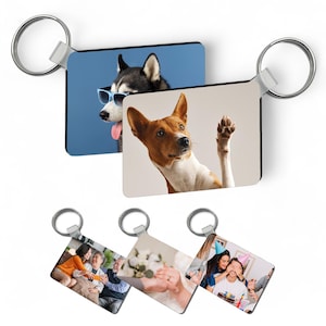 Puede incluir: Tres llaveros de fotos diferentes con un anillo plateado. El primer llavero presenta un perro blanco y negro con gafas de sol. El segundo llavero presenta un perro marrón y blanco con la pata levantada. El tercer llavero presenta un grupo de personas celebrando un cumpleaños.