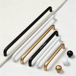 May include: A collection of cabinet hardware including long and short bar pulls in matte black, white, and gold finishes. One black pull features the text Evan Malik in white script. Three round knobs in matching black, white, and gold are included.