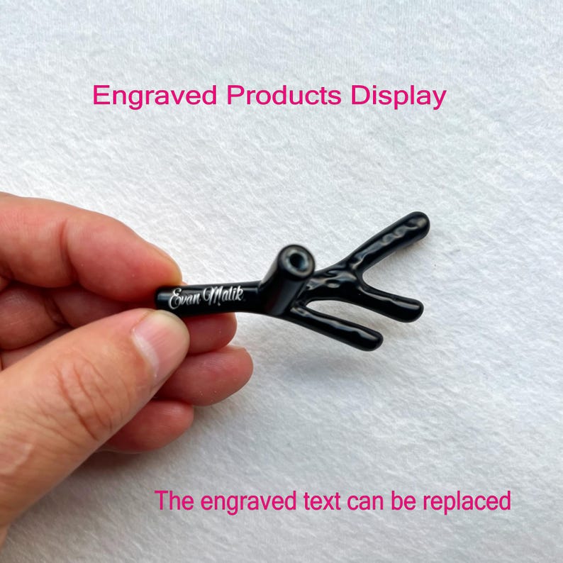 May include: A black, Y-shaped object with a smooth, glossy finish. The object features a cylindrical stem with a central hole and three branching arms. The text "Evan Malik" is engraved in a white, cursive script on the side of the stem.