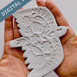 May include: A white, bird-shaped ornament with floral and leaf patterns. The ornament is held in a person's hands. The words "DIGITAL FILE" are printed diagonally across the top left corner.