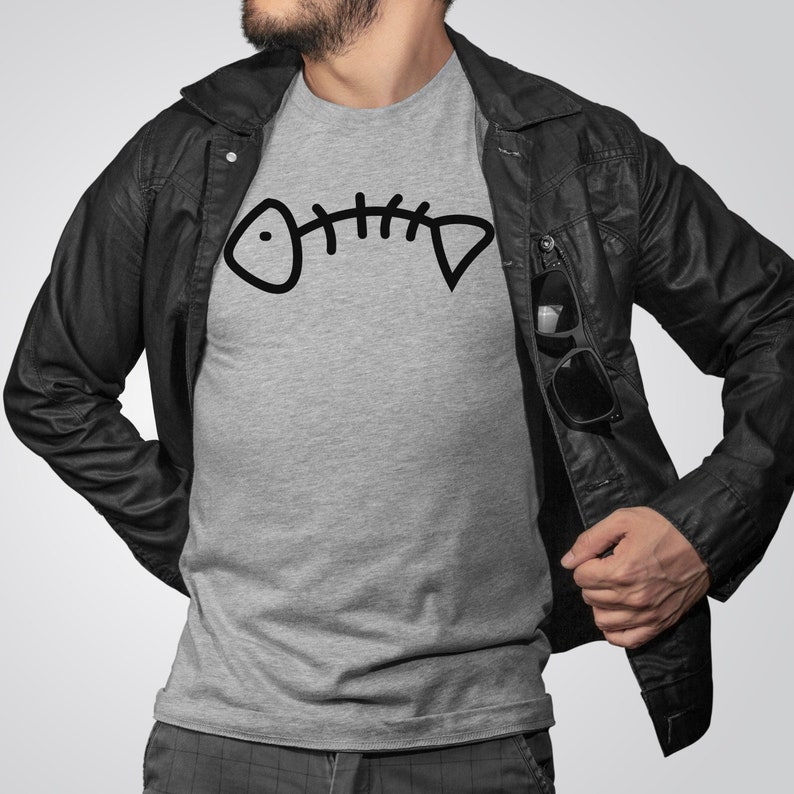 May include: A gray t-shirt with a black fishbone graphic. The t-shirt is being worn by a person wearing a black leather jacket.