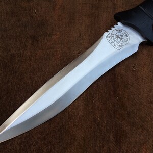 May include: A silver knife with a black handle. The handle has a circular emblem with the text "Raccoon Police Dept."