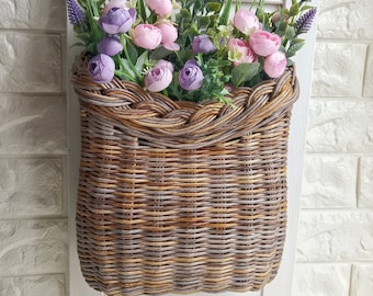 Basket on the door. Rounded flower basket. Wicker basket of motley color, decoration of the front door. Hanging basket on the door.