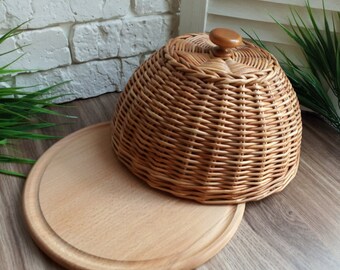 Round board with wicker lid. The lid covers the food. Punnet. Wooden serving board with wicker lid. Brown storage.