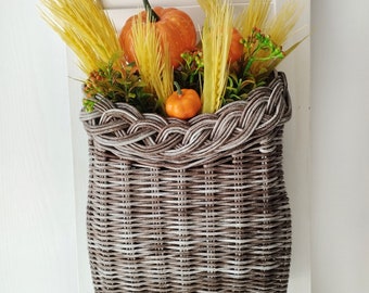 Basket on the door. Round flower basket. Brown wicker basket, front door decoration. Hanging basket on the door.