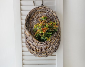 Basket on the door. Oval flower basket.Front door decoration. Straw-colored wicker basket, front door decoration.Hanging basket on the door.