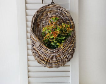 Basket on the door. Oval flower basket.Front door decoration. Straw-colored wicker basket, front door decoration.Hanging basket on the door.